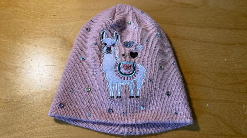 Fertige rosa Mütze mit Lama-Motiv und aufgeklebten Strasssteinen.